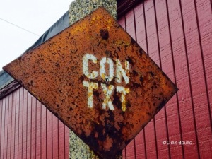 Rusty sign with "CON TXT" written on it, spotted near abandoned train tracks